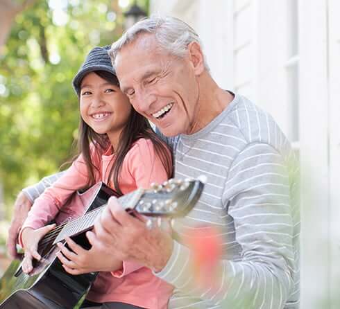 senior man teaching his granddaughter to play guitar