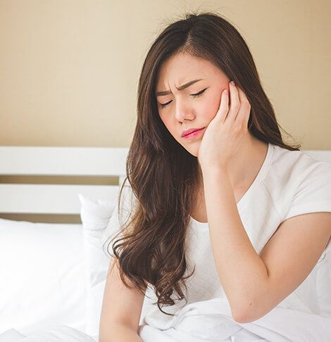 woman holding her jaw in pain