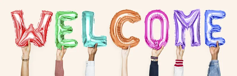 Diverse hands hold up multicolored balloon letters that say WELCOME