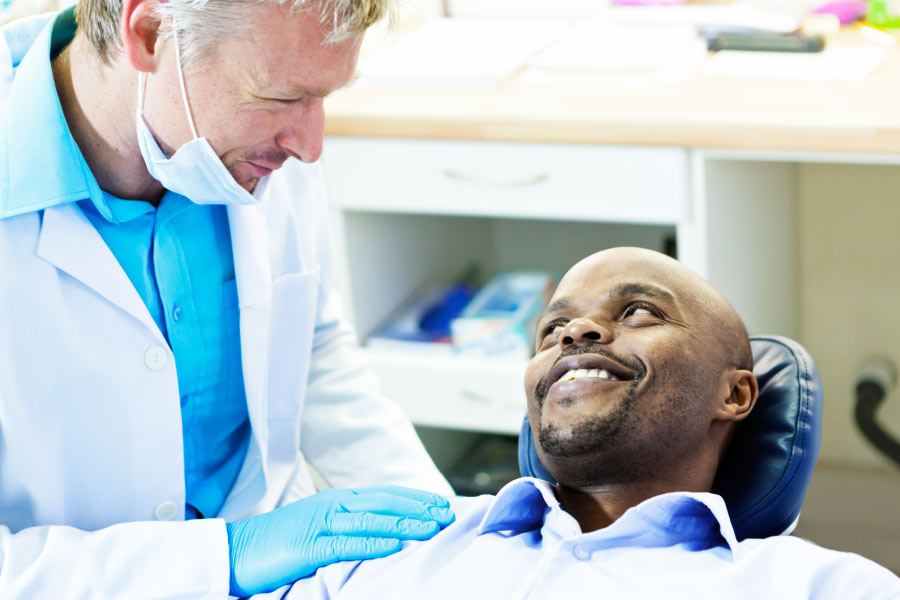 man sits in the dentist chair and discusses root canal with the dentist