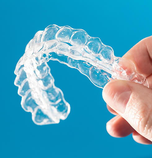 closeup of a someone holding a set of clear aligners